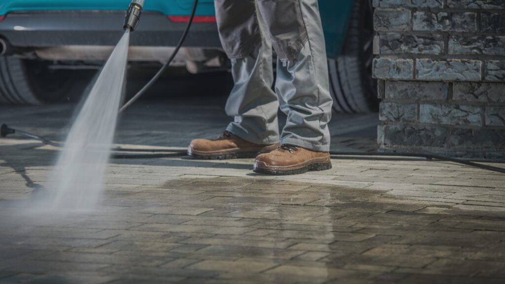 man washing stamped concrete driveway