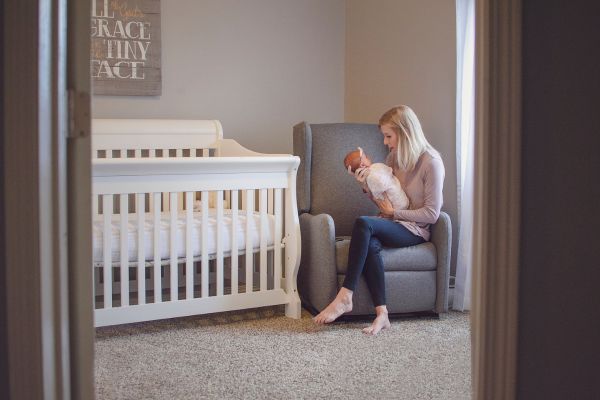 person sits in nursery chair holding baby