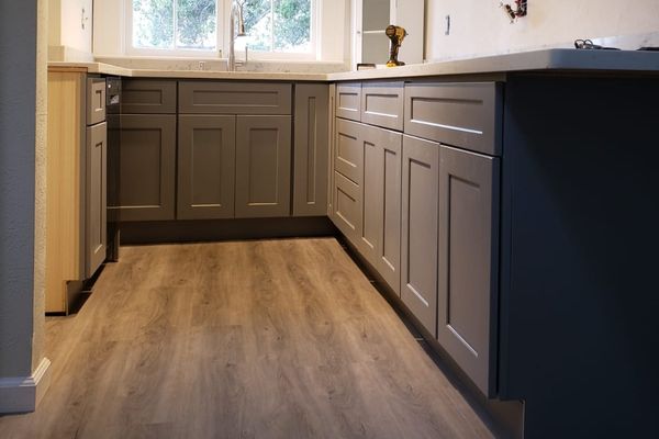 Elegant dark gray shaker-style kitchen cabinets paired with light natural wood flooring.
