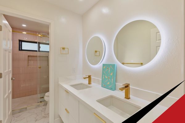 Modern luxury bathroom remodel featuring a sleek white double vanity, gold hardware, and glowing circular backlit mirrors.